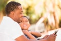 African American Father and Mixed Race Son Using Computer Tablet on Bench in Park Royalty Free Stock Photo