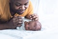 An African American father is playing tease with his 12-day-old baby newborn son lying in bed Royalty Free Stock Photo