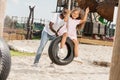 african american father pushing daughter on tire swing