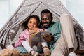 african american father reading book with child and smiling in