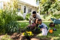 African american father and son digging dirt for planting flowers on field in backyard Royalty Free Stock Photo