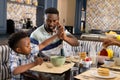 African american father and son giving high-five to each other while having breakfast at home Royalty Free Stock Photo