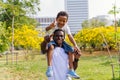 African American father and son piggyback in park. Fatherhood and happy family lifestyle concept