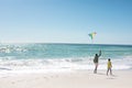 African american father and son running with kite at beach on sunny day with copy space Royalty Free Stock Photo