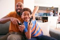 African American Father And Son Sitting On Sofa At Home Playing Video Game Together Royalty Free Stock Photo