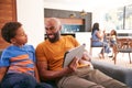 African American Father And Son Sitting On Sofa At Home Using Digital Tablet Royalty Free Stock Photo