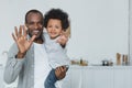 african american father and son waving hands