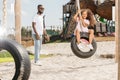 african american father standing near smiling daughter on tire swing