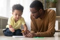 African American father and toddler son drawing colorful pencils together Royalty Free Stock Photo