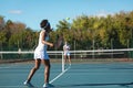 African american female athlete playing tennis game with caucasian competitor at court on sunny day