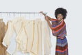 African American female designer with sewing patterns on clothes rack over gray background Royalty Free Stock Photo