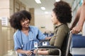 African American female doctor checks patient girl in wheelchair at hospital