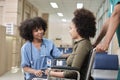 African American female doctor checks patient girl in wheelchair at hospital