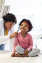 African american female doctor examining girl patient using otoscopy at hospital