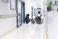 African american female doctor talking with senior female patient in wheelchair in hospital corridor Royalty Free Stock Photo