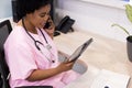 African american female doctor talking on smartphone and using tablet in hospital reception Royalty Free Stock Photo