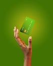 African american female hand and levitating template mockup Bank credit card with online service on green background