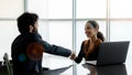African American female human resource manager sitting smiling shaking hand with Caucasian bearded male businessman applicant when Royalty Free Stock Photo