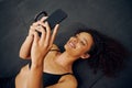 African American female lying on the floor and taking a photo. Beautiful mixed race woman smiling while taking the photo