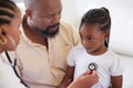 African american female paediatrician examining sick girl with stethoscope during visit with dad. Doctor checking heart Royalty Free Stock Photo