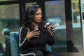 African american female speaking with a microphone while sitting on an armchair