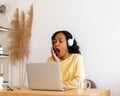 African-american female student yawning while listening to online lecture in headphones on laptop Royalty Free Stock Photo