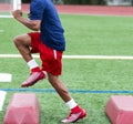 African American football player running over barriers at summer practice