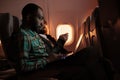 African american freelancer working on laptop during sunset flight