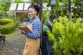 African American gardener holding clipboard while working in her conifer tree nursery garden center for evergreen and bonsai Royalty Free Stock Photo