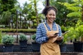 African American gardener nad nursery owner is holding clipboard while working in her conifer tree nursery garden center for Royalty Free Stock Photo