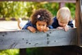 An African American girl and a blond boy lie on a wooden bridge