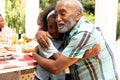 African American girl embracing with her grandfather during a family lunch in the garden