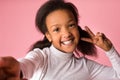 African-american girl grimacing and taking selfie, pink background Royalty Free Stock Photo
