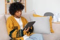 African american girl holding digital tablet touch screen typing scroll page at home. Woman with mobile tech device Royalty Free Stock Photo