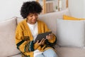 African american girl holding digital tablet touch screen typing scroll page at home. Woman with mobile tech device Royalty Free Stock Photo