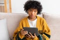 African american girl holding digital tablet touch screen typing scroll page at home. Woman with mobile tech device Royalty Free Stock Photo