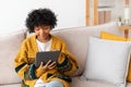 African american girl holding digital tablet touch screen typing scroll page at home. Woman with mobile tech device Royalty Free Stock Photo