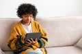 African american girl holding digital tablet touch screen typing scroll page at home. Woman with mobile tech device Royalty Free Stock Photo