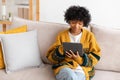 African american girl holding digital tablet touch screen typing scroll page at home. Woman with mobile tech device Royalty Free Stock Photo