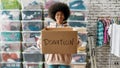 African american girl holding donation box and looking at camera, posing in front of boxes full of clothes, Young Royalty Free Stock Photo