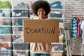 African american girl holding donation box and smiling at camera, posing in front of boxes full of clothes, Young Royalty Free Stock Photo