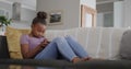 African american girl sitting on sofa and using tablet, slow motion, unaltered