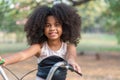 African American girl smiling and looking at camera while riding a bicycle in the park Royalty Free Stock Photo