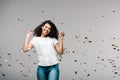 African american girl smiling near shiny confetti while standing on grey Royalty Free Stock Photo