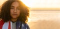 African American Girl Teenager Wrapped in USA Flag on a Beach at Sunset Royalty Free Stock Photo