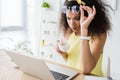 African american girl touching glasses while looking at laptop and holding cup of coffee Royalty Free Stock Photo