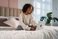 African American girl using laptop in bed at home office typing chatting reading writing email. Young black woman having Royalty Free Stock Photo