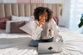 African American girl using laptop in bed at home office typing chatting reading writing email. Young black woman having Royalty Free Stock Photo