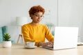 African american girl using laptop at home office looking at screen typing chatting reading writing email. Young woman Royalty Free Stock Photo