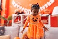 African american girl wearing pumpkin costume playing with soap bubbles at home Royalty Free Stock Photo